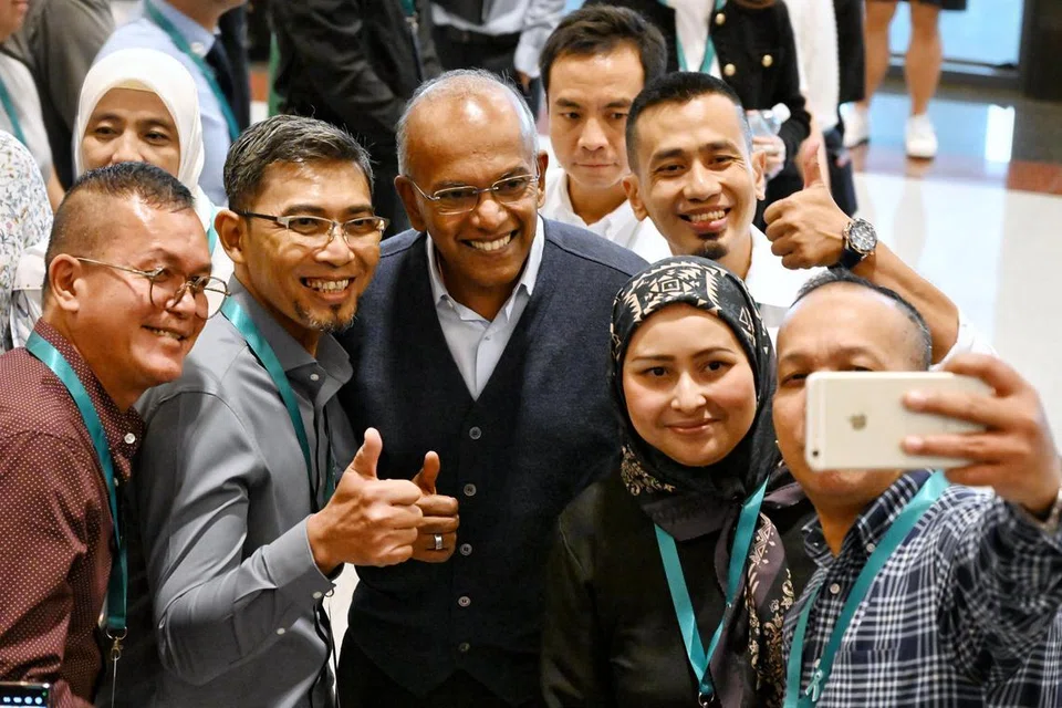 Encik Shanmugam bergambar bersama bekas penyalah guna dadah dan keluarga mereka di majlis resepsi di Bangunan Parlimen pada 8 Mei. 
