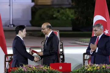 Perdana Menteri, Encik Lawrence Wong (kiri), menerima watikah pelantikan daripada Presiden Tharman Shanmugaratnam semasa majlis angkat sumpah di Istana pada 15 Mei, sambil disaksikan Ketua Hakim  Sundaresh Menon.