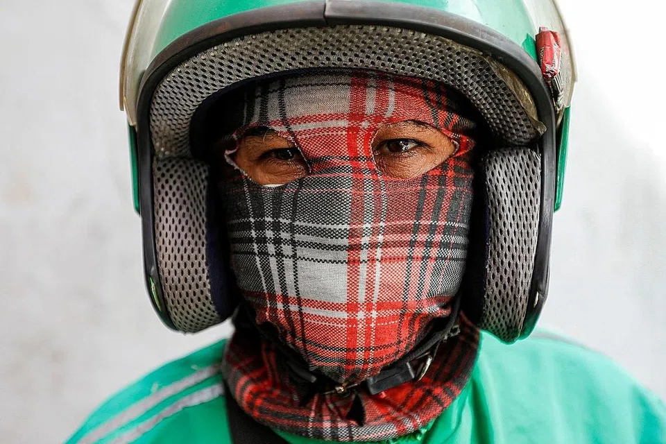 INDONESIA. Penunggang motosikal dari Jakarta, Indonesia menggunakan pelitup khusus buat dirinya. - Foto REUTERS