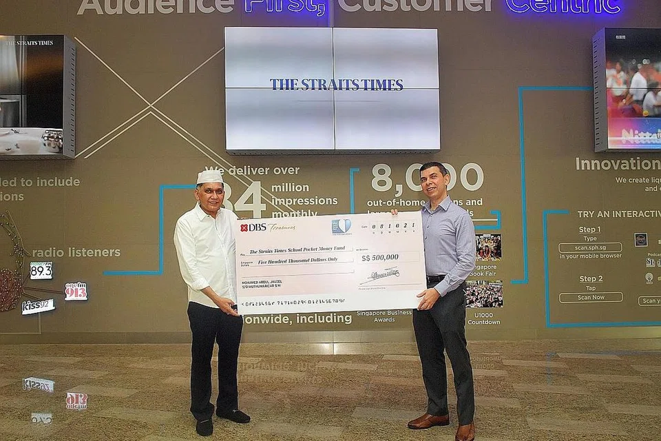 TERUS MENDERMA: Encik Mohamed Abdul Jaleel menyampaikan cek bernilai $500,000 bagi Dana Wang Saku Sekolah The Straits Times (STSPMF) kepada ketua dana yang juga Editor The Straits Times Warren Fernandez. - Foto BH oleh ALPHONSUS CHERN