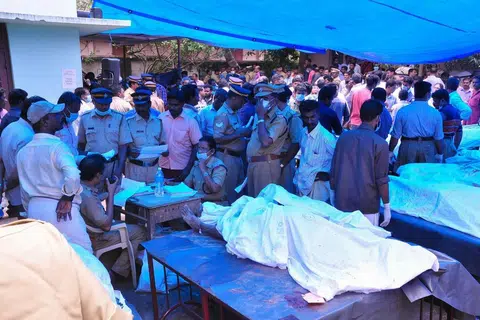 Para pegawai berdiri di sisi mayat yang diletak di luar hospital sedang saudara-mara cuba mengenal pasti korban kebakaran besar di Kuil Puttingal Devi pada Ahad (10 April). 
