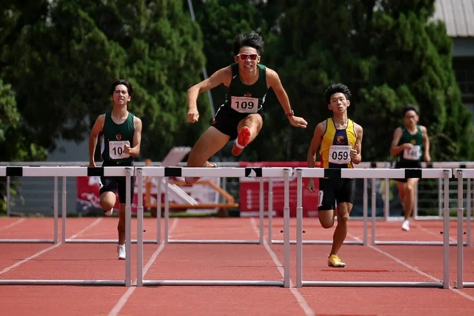 Atlet Institusi Raffles (RI), Daryen Ko (dua dari kiri), melepasi pagar terakhir sebelum memenangi acara final 400 meter lompat pagar lelaki Divisyen A dengan rekod baru 53.75 saat di Stadium Choa Chu Kang pada 13 April.