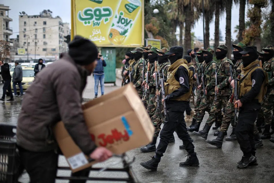Seorang lelaki melintasi barisan tentera Syria semasa perarakan tentera yang dianjurkan oleh Kementerian Pertahanan Syria bersempena tamat latihan lebih 300 askar di bandar Aleppo, utara Syria, pada 12 Februari 2025.