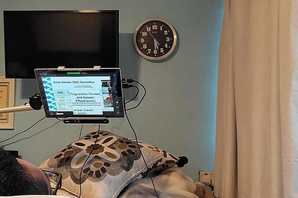 DUGAAN BUKAN PENGHALANG: Riz Sunawan, 42 tahun, menghadiri mesyuarat Bulan Bahasa secara maya dari bilik rumahnya dengan memanfaatkan teknologi pergerakan mata, Tobii, yang membolehkan beliau berkomunikasi dan menaip tanpa memerlukan bantuan orang lain. Peranti Tobii kelihatan dilekatkan di bahagian bawah skrin. - Foto ihsan RIZ SUNAWAN 