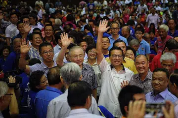 SOKONGAN MASYARAKAT CINA: Presiden Persatuan Cina Malaysia (MCA), Datuk Seri Liow Tiong Lai (berkacamata bingkai gelap dan berkemeja lengan pendek warna putih) dan Anggota Parlimen Ayer Hitam (Johor), Encik Wee Ka Siong (berbaju gelap, sebelah kirinya) melambai kepada orang ramai sebelum bermula perhimpunan MCA di Johor Jaya kelmarin. - Foto-foto BH oleh Mark Cheong