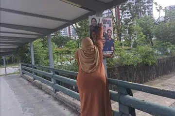Cik Liyana Dhamirah dilihat menurunkan poster pasukannya yang bertanding di GRC Jurong East-Bukit Batok pada hari bertenang setelah menerima notis  daripada ELD pada 2 Mei.