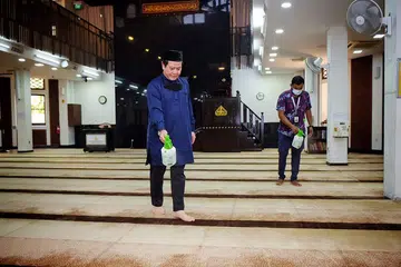 KEBERSIHAN TERUS DIJAGA: Selepas solat qiamullail, masjid ditutup untuk disanitasi, seperti yang dilakukan Encik Azman Mohd Ariffin (kiri) dan seorang kakitangan di Masjid Kampung Siglap, sebelum dibuka semula untuk solat subuh. - Foto BH oleh KHALID BABA