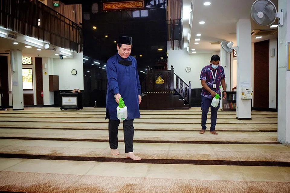KEBERSIHAN TERUS DIJAGA: Selepas solat qiamullail, masjid ditutup untuk disanitasi, seperti yang dilakukan Encik Azman Mohd Ariffin (kiri) dan seorang kakitangan di Masjid Kampung Siglap, sebelum dibuka semula untuk solat subuh. - Foto BH oleh KHALID BABA