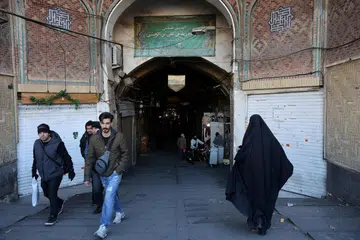 Orang ramai melintasi kedai-kedai di Tehran yang ditutup ekoran protes  terhadap kos sara hidup dan ekonomi Iran yang semakin merudum.