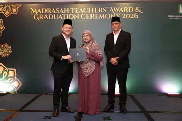 Pemangku Menteri Bertanggungjawab bagi Ehwal Masyarakat Islam, Encik Zaqy Mohamad (kiri) menyampaikan Anugerah Khidmat Setia Madrasah  kepada Ustazah Tapsirah Hassan, di Majlis Anugerah Guru Madrasah dan Graduasi (MTAGC)  di Pusat Konvensyen Suntec City pada 26 Ogos. Turut bersama mereka di atas pentas, Ketua Eksekutif Majlis Ugama Islam Singapura (MUIS), Encik Kadir Maideen.