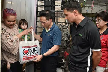TERIMA HABUAN: Cik Dalia Mansor (mendukung anak) menerima beg yang diisi makanan dan keperluan rumah dari Mayor CDC North East Encik Desmond Choo (tengah) dan Pengarah Urusan Grab Singapore, Encik Yee wee Tang (dua dari kanan). - Foto BH oleh MOHD KHALID BABA