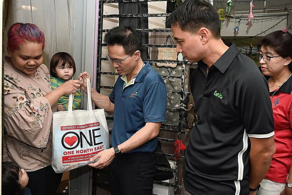 TERIMA HABUAN: Cik Dalia Mansor (mendukung anak) menerima beg yang diisi makanan dan keperluan rumah dari Mayor CDC North East Encik Desmond Choo (tengah) dan Pengarah Urusan Grab Singapore, Encik Yee wee Tang (dua dari kanan). - Foto BH oleh MOHD KHALID BABA