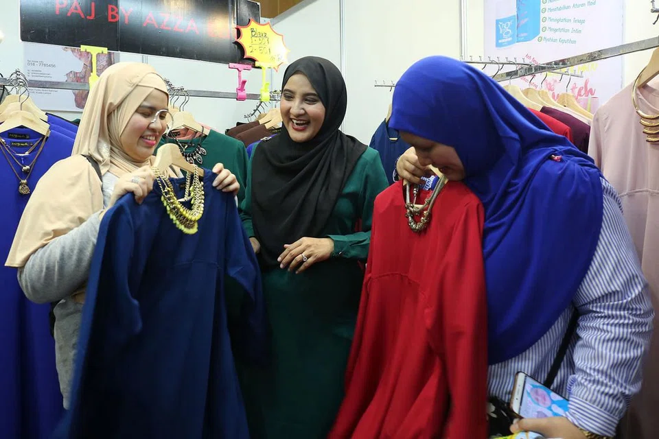 TEMUI PEMINAT SAMBIL BERNIAGA: Azza Elite (tengah) merebut peluang mendekati peminat Singapura yang sentiasa meluangkan masa mendapatkan produk jualannya setiap kali beliau ke sini. - Foto BH oleh PUTRI MARDHIYAH YAZID