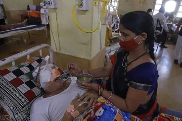 DERITA: Seorang atendan dilihat bersebelahan pesakit Covid-19 yang turut menghidap penyakit kulat hitam di Kolej Perubatan Netaji Subhash Chandra Bose di Jabalpur, India. - Foto AFP