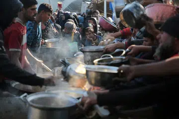 Penduduk Palestin berkumpul untuk menerima makanan yang dimasak di dapur amal di Khan Younis, selatan Gaza, pada 2 Januari sedang perunding Israel meneruskan rundingan di Doha dengan meletakkan pembebasan tebusan sebagai tuntutan utama.