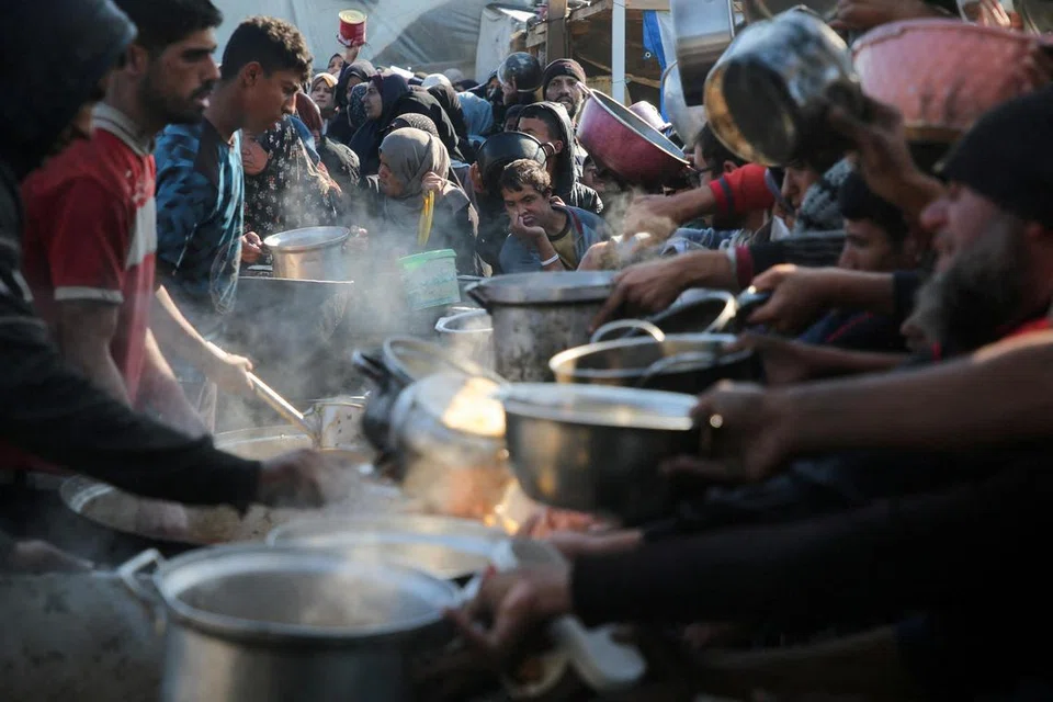 Penduduk Palestin berkumpul untuk menerima makanan yang dimasak di dapur amal di Khan Younis, selatan Gaza, pada 2 Januari sedang perunding Israel meneruskan rundingan di Doha dengan meletakkan pembebasan tebusan sebagai tuntutan utama.