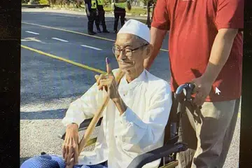 MASIH BERSEMANGAT MENGUNDI: Encik Mohd Nor (berkerusi roda), yang datang bersama anaknya, Encik Sobri, tetap bersemangat membuang undi di Sekolah Kebangsaan Bandar Beris Jaya, dekat Sik, pada Sabtu.