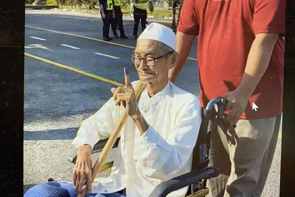 MASIH BERSEMANGAT MENGUNDI: Encik Mohd Nor (berkerusi roda), yang datang bersama anaknya, Encik Sobri, tetap bersemangat membuang undi di Sekolah Kebangsaan Bandar Beris Jaya, dekat Sik, pada Sabtu.