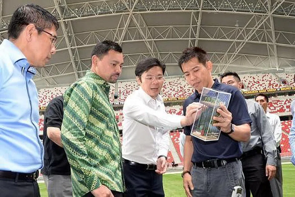 KUNJUNGAN TETAMU ISTIMEWA: Putera Haji Al-Muhtadee Billah (berbaju hijau) mendengar taklimat tentang Hab Sukan Singapura dan Stadium Negara semasa lawatan beliau ke sana. Antara lain, beliau ditemani Encik Lawrence Wong (tengah) dan Dr Mohamad Maliki (kiri). - Foto JOHARI RAHMAT