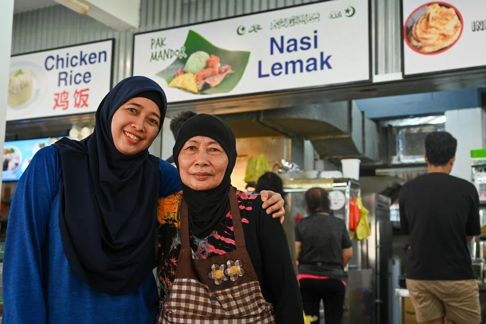 KEKALKAN HARGA BERPATUTAN: Pemilik gerai Pak Mandor Nasi Lemak, Cik Misniati Sagio (kanan), berniaga nasi lemak berperisa pandan yang berpatutan sejak tiga dekad lalu di kawasan Yishun bersama anaknya, Cik Jumianti. 