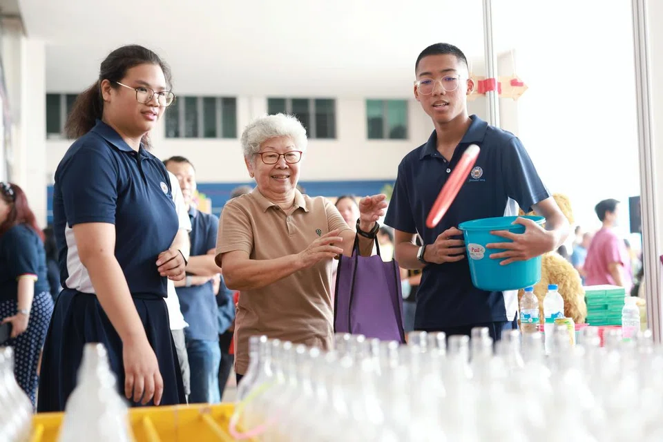 HULUR SUMBANGAN: Sukarelawan belia dari Sekolah Menengah Kuo Chuan Presbyterian, Mohamad Miqa Ariyan Mohamad Nizal (kanan) bersama temannya, Annette Chua (kiri) menyumbang tenaga dan membantu warga emas dalam acara ‘Let’s Carnival’ pada Sabtu. 