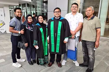 KONGSI KEJAYAAN: Encik Muhammad Isa Ali (tiga dari kanan) bersama tunangnya, Cik Nurul Amirah Zulkanain (tiga dari kiri), sama-sama mendapat diploma daripada Politeknik Republic. Bersama dalam gambar adalah ahli keluarga mereka. - Foto ihsan MUHAMMAD ISA ALI