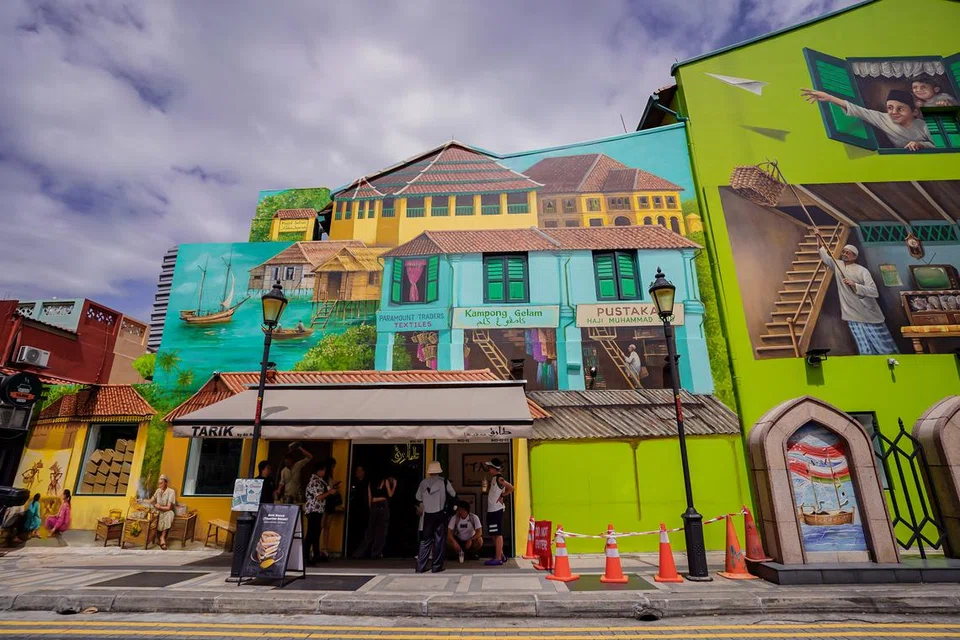GAMBARAN MASA LAMPAU: Mural setinggi tiga tingkat yang sedang dilukis Yip Yew Chong di 92 Arab Street menggambarkan zaman lampau Kampong Gelam.