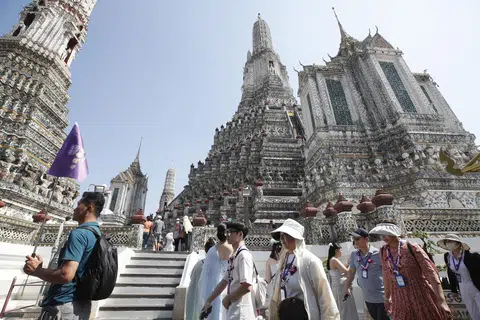Seorang jurupandu membawa sekumpulan pelancong asing mengunjungi kuil Wat Arun di Bangkok, Thailand pada 6 Januari 2025.