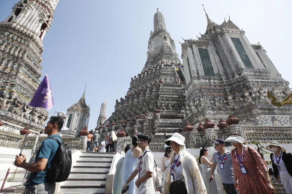 Seorang jurupandu membawa sekumpulan pelancong asing mengunjungi kuil Wat Arun di Bangkok, Thailand pada 6 Januari 2025.