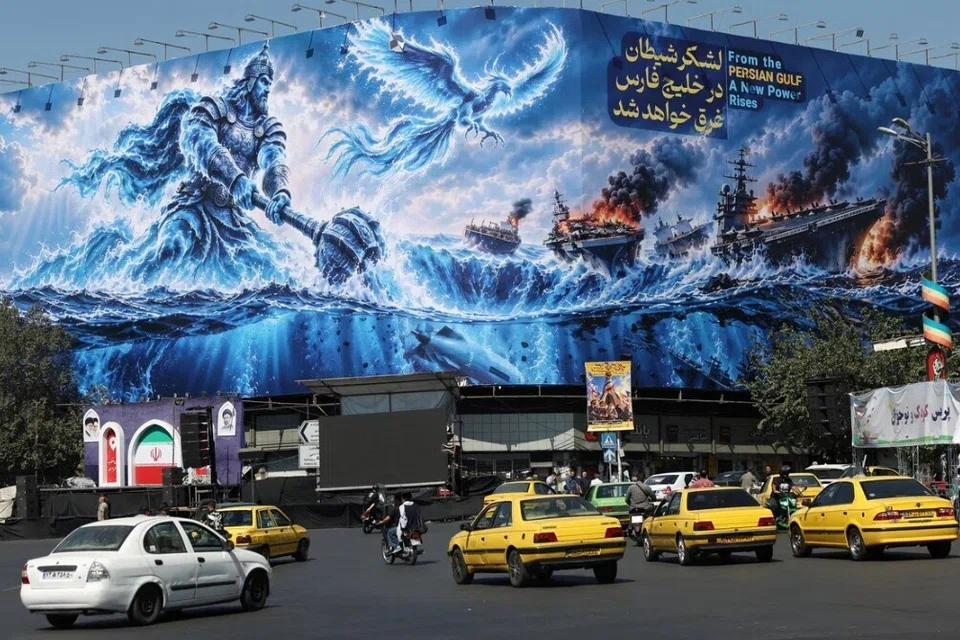 Orang ramai memandu di hadapan papan iklan mengenai Selat Hormuz yang dipasang pada sebuah bangunan di Teheran, Iran.
