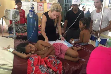 PUNCAK WABAK: Cik Jessica Manning merawat seorang gadis yang sakit di Hospital Rujukan Daerah Kampong Speu ketika meningkatnya wabak denggi di Krong Chbar Mon, Kemboja, Julai 2019. Wad pediatrik 20 katil menampung 100 anak yang sakit pada puncak wabak ini, dengan dua anak setiap katil dan orang ramai memenuhi kaki lima, bangku dan buai rajut yang digantung ke pokok berdekatan. - Foto REUTERS