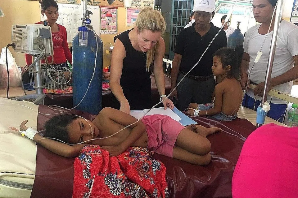 PUNCAK WABAK: Cik Jessica Manning merawat seorang gadis yang sakit di Hospital Rujukan Daerah Kampong Speu ketika meningkatnya wabak denggi di Krong Chbar Mon, Kemboja, Julai 2019. Wad pediatrik 20 katil menampung 100 anak yang sakit pada puncak wabak ini, dengan dua anak setiap katil dan orang ramai memenuhi kaki lima, bangku dan buai rajut yang digantung ke pokok berdekatan. - Foto REUTERS