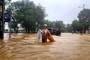 Seorang wanita berbaju hujan meredah jalan yang dinaiki air di bandar Hue pada 28 Oktober 2025. Bandar di Vietnam tengah itu merekodkan lebih satu meter hujan dalam tempoh 24 jam, memecahkan rekod kebangsaan yang dicatat lebih dua dekad lalu, menurut kementerian alam sekitar. 