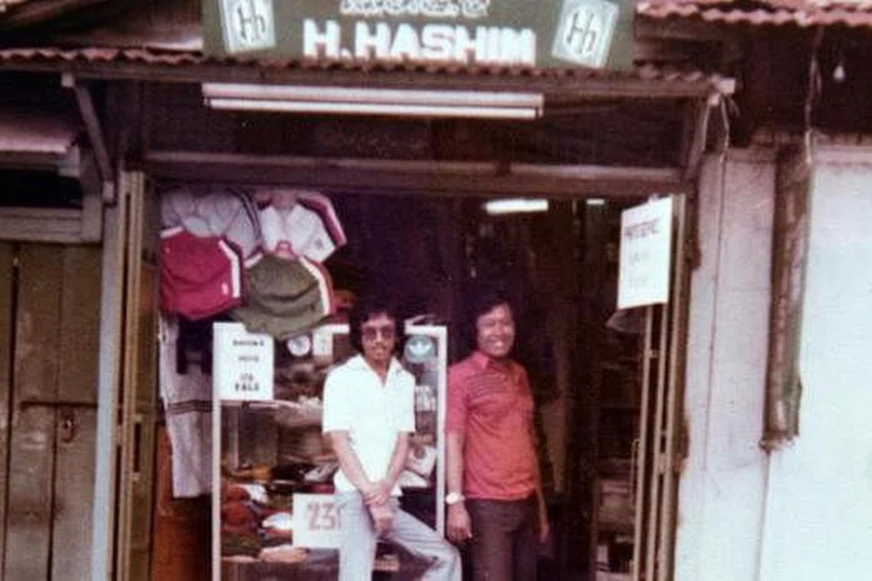 TIDAK DITELAN ZAMAN: Gambar yang diambil sekitar 1970-an ini menunjukkan Haji Abdul Aziz (kiri) berdiri di depan kedai datuknya itu di Geylang. - Foto HAJI HASHIM
