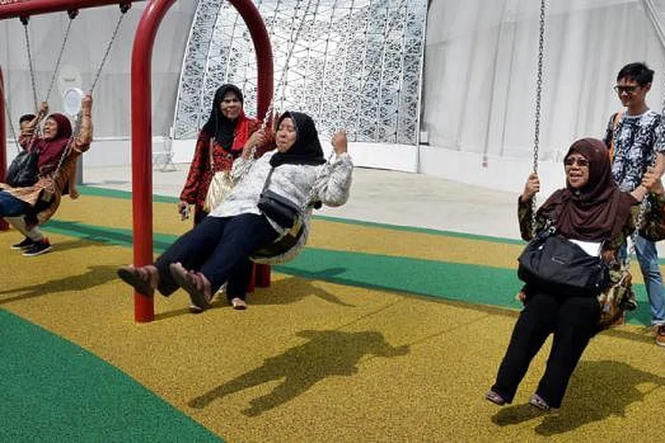 BUAI LAJU-LAJU: Selain mendapat gambaran tentang masa depan Singapura di pameran Future of Us, Cik Zainon Ibrahim (kanan) dan teman-temannya berasa seronok dapat bermain buai-buai yang tersedia untuk para pengunjung. - Foto M.O. SALLEH