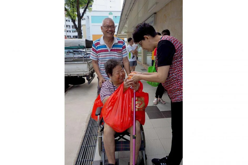 KONGSI 'MOOD': Penduduk di kawasan Haig Road, Joo Seng dan Eunos Crescent berkongsi 'mood' perayaan Tahun Baru Cina bersama Anggota Parlimen (AP) GRC Marine Parade, Profesor Fatimah Lateef (kanan) yang telah mengagihkan buah oren kepada penduduk dan peniaga kawasan tersebut. - Foto FATIMAH ABDUL LATEEF