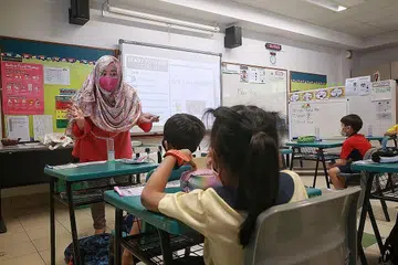 LENGKAPI KEMAHIRAN: Guru AED seperti Cik Mastura M Hashim membantu pelajar menyesuaikan diri apabila melangkah ke darjah satu . - Foto BH oleh KEVIN LIM