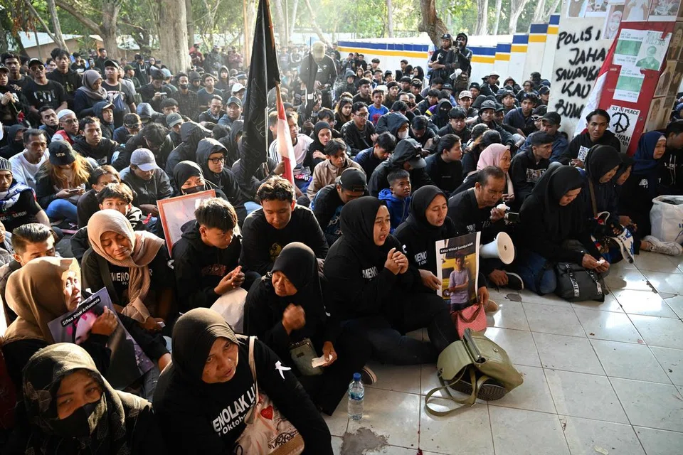 PANJATKAN DOA: Keluarga mangsa dengan potret anak mereka yang meninggal dunia berkumpul bersama-sama dengan peminat bola sepak semasa memperingati ulang tahun pertama rempuhan  di Stadium Kanjuruhan pada Oktober 2022 yang mengorbankan 135 orang dalam salah satu tragedi bola sepak terburuk di Indoensia.
