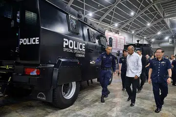 KEUPAYAAN POLIS: Menteri Ehwal Dalam Negeri merangkap Undang-undang, Encik K. Shanmugam (berbaju putih) ditemani Pemangku Pesuruhjaya Polis, Encik Jerry See (kanan) semasa meninjau kenderaan serangan taktikal di Pameran dan Seminar Pelan Kerja Polis di Singapore Expo pada Jumaat. - Foto-foto ST