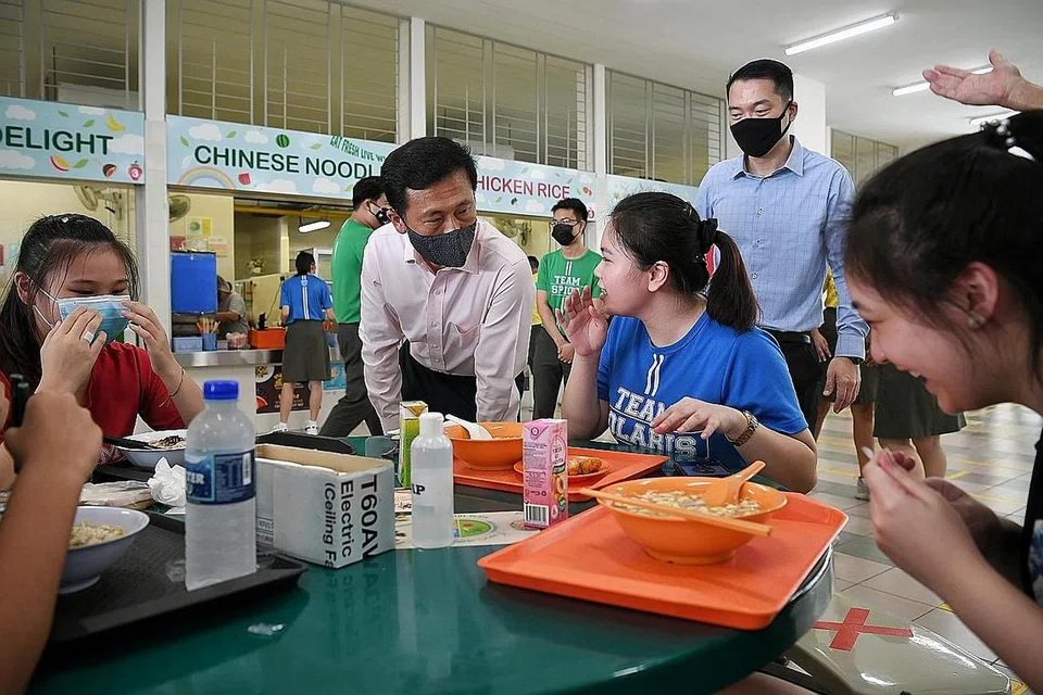 DEKATI GOLONGAN MUDA: Encik Ong beramah dengan beberapa pelajar menengah empat semasa waktu makan. Para pelajar dihiburkan dengan konsert dalam talian yang dipersembahkan oleh kumpulan pelajar kesenian sekolah tersebut. Di belakang mereka ialah pengetua Sekolah Menengah Tampines, Encik Shane Kwok. - Foto BH oleh KUA CHEE SIONG