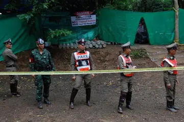 KEADAAN GENTING: Pegawai polis dan kakitangan keselamatan mengawal kawasan mulut gua Tham Luang.