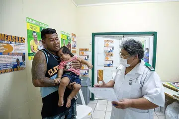 USAHA BENDUNG WABAK: Seorang jururawat Cik Fa'atafa Tavita bercakap bersama sebuah keluarga mengenai suntikan penyakit demam campak di ibu kota Samoa, Apia. Samoa menjalankan pemvaksinan besar-besaran awal bulan ini bagi membendung wabak campak yang membunuh berpuluh-puluh kanak-kanak. - Foto UNICEF