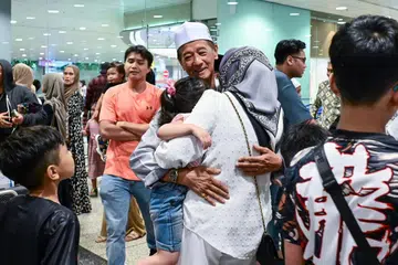 SAMBUT KETIBAAN: Seorang jemaah kelihatan dipeluk ahli keluarga dekat pintu keluar Terminal 3, Lapangan Terbang Changi.