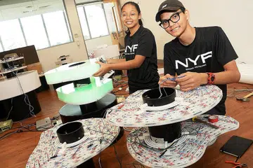 MENYIAPKAN STRUKTUR SENI CAHAYA: Cik Nur Najiba Mohammad Noh dan Encik Shukran Shukor adalah antara 12 pelajar Politeknik Nanyang yang menghasilkan struktur seni cahaya, Ataraxia. Cik Nur Najiba memegang salah satu kontur pemancar cahaya manakala Encik Shukran bertanggungjawab daripada aspek pemasangan wayar dan kejuruteraan. - Foto JOHARI RAHMAT