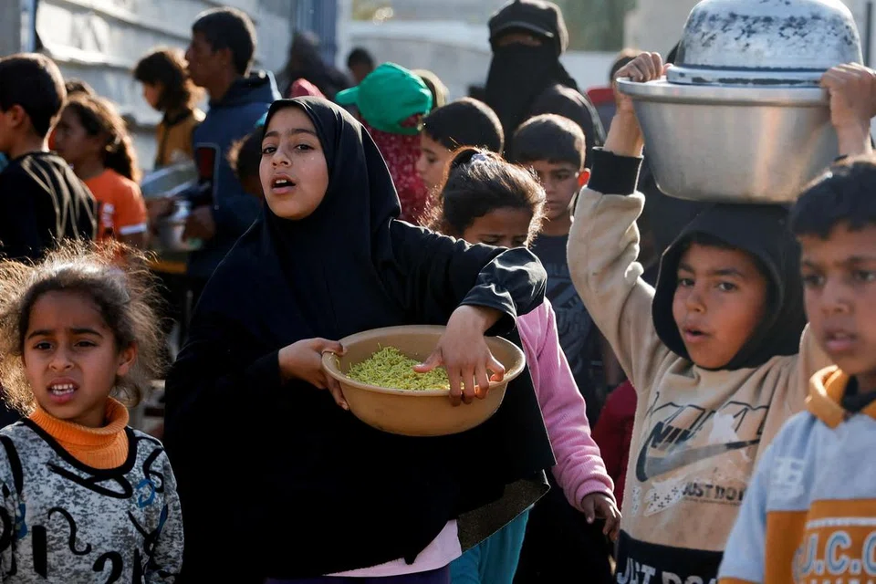 Seorang kanak-kanak perempuan Palestin menerima makanan yang dimasak oleh dapur kebajikan sempena bulan suci Ramadan, di Rafah, selatan Semenanjung Gaza, pada 13 Mac 2025.