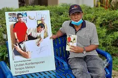 BUKU TERAPI MELAYU: Encik Saini Salleh, seorang mantan wartawan Berita Harian, bersama poster buku 'Urutan Kontemporari Terapis Melayu Singapura' yang ditulis beliau. - Foto ihsan HAJI ABDUL LATIFF AHMAD