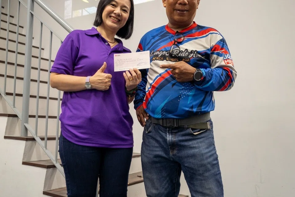 Encik Rahim menyerahkan cek kepada Cik Tiffany Tei, Pengurus Besar Free Food For All, pada 29 September.