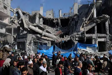 Para penduduk Palestin  membeli barangan di pasar bersebelahan runtuhan bangunan akibat pengeboman Israel di kem pelarian Nuseirat, Bandar Gaza, ketika rundingan gencatan senjata berlangsung.