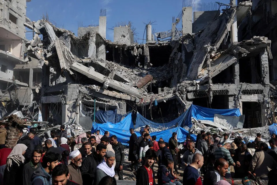 Para penduduk Palestin  membeli barangan di pasar bersebelahan runtuhan bangunan akibat pengeboman Israel di kem pelarian Nuseirat, Bandar Gaza, ketika rundingan gencatan senjata berlangsung.