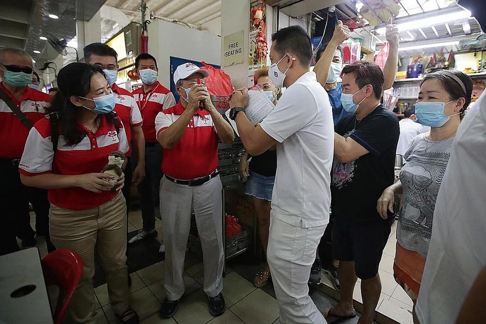 SALING HORMAT: Calon PAP, Encik Yip Hon Weng (baju putih) terserempak dengan calon Parti Kemajuan Singapura (PSP) Cik Kayla Low (kiri) dan Dr Tan Cheng Bock di pusat penjaja makanan di Blok 628 Ang Mo Kio Avenue 4 semasa mereka berkempen dan bertemu penduduk di SMC Yio Chu Kang. - Foto BH oleh GIN TAY 